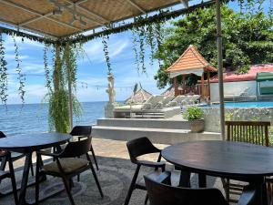 two tables and chairs on a patio next to the water at Bahari Beach Amed in Amed