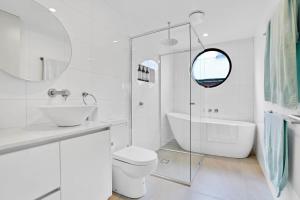 a white bathroom with a tub and a sink and a toilet at Stunning Apartment in the CBD with Parking & WiFi in Launceston +13 photos