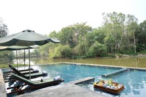 a large swimming pool with chairs and an umbrella at Kirirom Hillside Resort in Kampong Speu