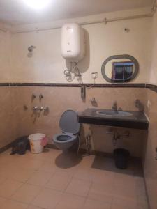 uma casa de banho com um WC, um lavatório e um espelho. em Indraprastha Cottage em Dharmsala