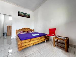 1 dormitorio con cama de madera y silla roja en Alan's Homestay en Kuripan