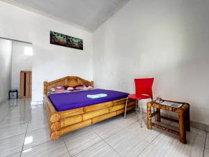 a bedroom with a wooden bed and a red chair at Alan's Homestay in Kuripan