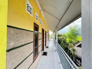 a hallway of a yellow building with a person walking down it at Alan's Homestay in Kuripan