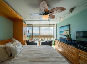 a bedroom with a bed with a ceiling fan and a television at Beachfront Condo in Paradise in Waianae