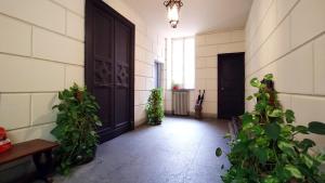 un pasillo con una puerta negra y algunas plantas en Palazzo Galati Palermo, en Palermo