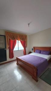 Hotel Shekinah Internacional في إسمرالداس: غرفة نوم مع سرير مع ملاءات أرجوانية ونافذة