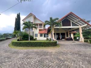 a house with palm trees in front of a driveway at Reddoorz Near BNS 2 in Tlekung