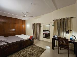 een slaapkamer met een bed, een bureau en een spiegel bij Willow - 2BHK in Bangalore