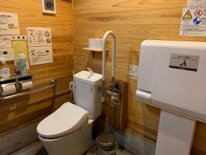 a bathroom with a toilet in a wooden wall at Boiboi Camp site Surrounded by Japanese Nature in Taketa