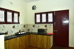una cocina con armarios de madera y una puerta roja en Narayani Resort - Serene resort with private swimming pool en Tiruvannāmalai