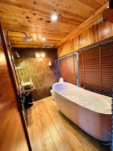 a large bath tub in a bathroom with wooden walls at Căn Hana ( Moon Villa Sóc Sơn) in Hanoi