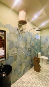 y baño con ducha, aseo y lavamanos. en Chaitali The Villa, en Santiniketan