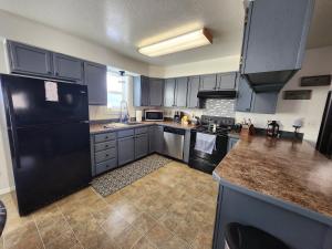 a kitchen with blue cabinets and a black refrigerator at Newly furnished relaxing stay in Fairbanks