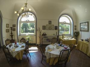 una sala da pranzo con due tavoli e due finestre di B&B Villa Ocsia a San Giorgio a Cremano