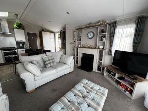 salon z białą kanapą i kominkiem w obiekcie Beautiful Caravan With Decking At Azure Seas Ref 32060az w mieście Lowestoft