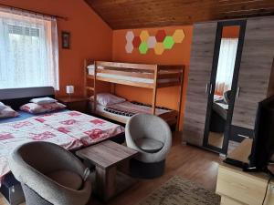 a bedroom with two bunk beds and two chairs at Fenyő Vendégház in Parádsasvár