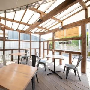 una cafetería con mesas y sillas de madera y ventanas en Asuka Hotel en Karatsu