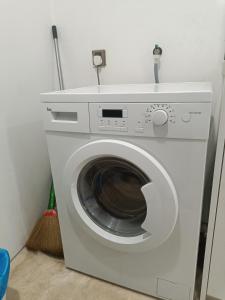 a white washing machine in a room with a broom at vortex klcc RR in Kuala Lumpur