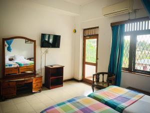 1 dormitorio con 2 camas, espejo y TV en Sharon Inn, en Kandy