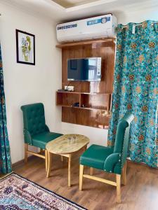 a room with two chairs and a table and a tv at Pandith Exotics Hotel And Restaurant in Gulmarg
