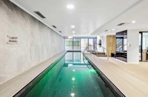 an indoor swimming pool with green water in a building at Collins Street City Stay - 2 Min to Southern Cross in Melbourne