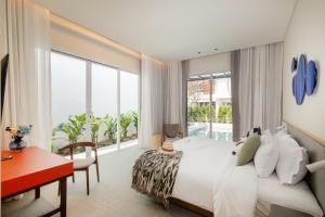 a bedroom with a bed and a desk and a large window at Veranda Resort & Villas Hua Hin Cha Am in Cha Am +143 photos