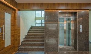 un escalier avec un ascenseur en verre dans un bâtiment dans l'établissement Treebo Global Stay, Uttarahalli, à Bangalore