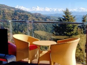 a table and chairs on a balcony with mountains at Fairmont cottage Mukteshwar in Mukteswar