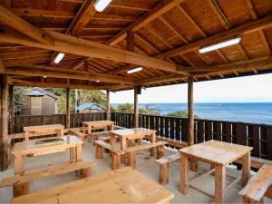 een groot houten paviljoen met picknicktafels en de oceaan bij Tonosaki Bungalow & BBQ - Vacation STAY 29542v in Tsushima