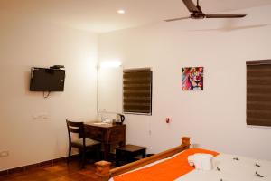 um quarto com uma cama, uma secretária e uma televisão em Marari Beach Palace em Mararikulam