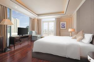 a bedroom with a white bed and a large window at Royal Lotus Hotel Danang in Danang