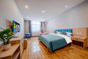 Schlafzimmer mit einem Bett, einem Schreibtisch und einem TV in der Unterkunft Mando Hotel - Kunming Changshui International Airport in Kunming