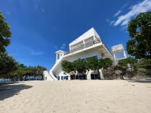 a white building on the beach with trees in front at Chalaroste Place by SMS Hospitality in Bolinao