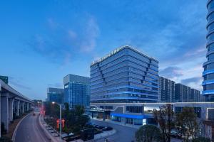 a large glass building in a city with a street at Howard Johnson Airport Serviced Residence Changsha in Changsha