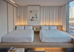 a hotel room with two beds and a window at UH Suite The Seoul in Seoul