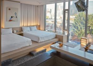 a hotel room with two beds and a window at UH Suite The Seoul in Seoul