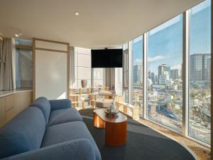 a living room with a blue couch and a large window at UH Suite The Seoul in Seoul
