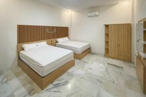 a small bedroom with two beds and a bathroom at Urbanview Hotel Tritia Lampung in Kedaton