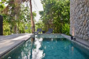 einen Pool mit zwei Stühlen neben einem Gebäude in der Unterkunft Villa Papaya @ Kamala Beach in Kamala Beach