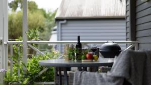 a table with a bottle of wine and fruit on a balcony at Lakeside Suite 2 - Lake View & Spa Bath in Daylesford
