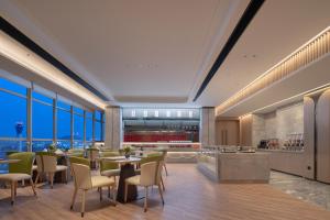 un restaurante con mesas, sillas y ventanas en Howard Johnson Airport Serviced Residence Changsha, en Changsha