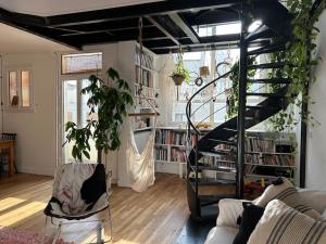 een woonkamer met een wenteltrap en boekenplanken bij Duplex apartment with terrace and closed parking - Stade Charléty Paris in Arcueil