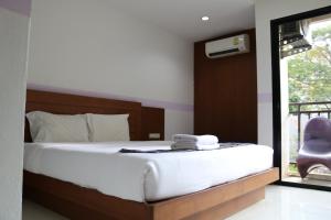 a bedroom with a bed with white sheets and a mirror at Diamond Crown in Patong Beach