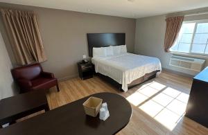 a hotel room with a bed and a chair and a table at Red Roof Inn Hayward in Hayward