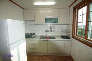 a kitchen with white cabinets and a white refrigerator at Yerae Pension in Seogwipo
