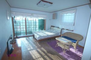 a bedroom with a bed and a chair and windows at Yerae Pension in Seogwipo