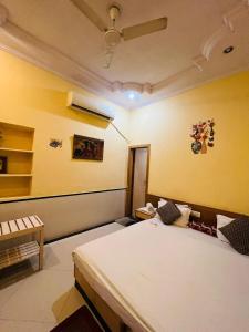 a bedroom with a white bed and a yellow wall at Hotel Payal Jaisalmer in Jaisalmer