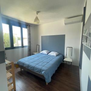 ein Schlafzimmer mit einem Bett mit einer blauen Decke in der Unterkunft Maison avec Piscine in Agde