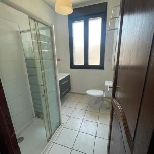 ein Bad mit einem WC und einer Glasdusche in der Unterkunft Maison avec Piscine in Agde