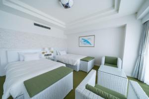 a white bedroom with two beds and a chair at Hotel Atollemerald Miyakojima in Miyako-jima